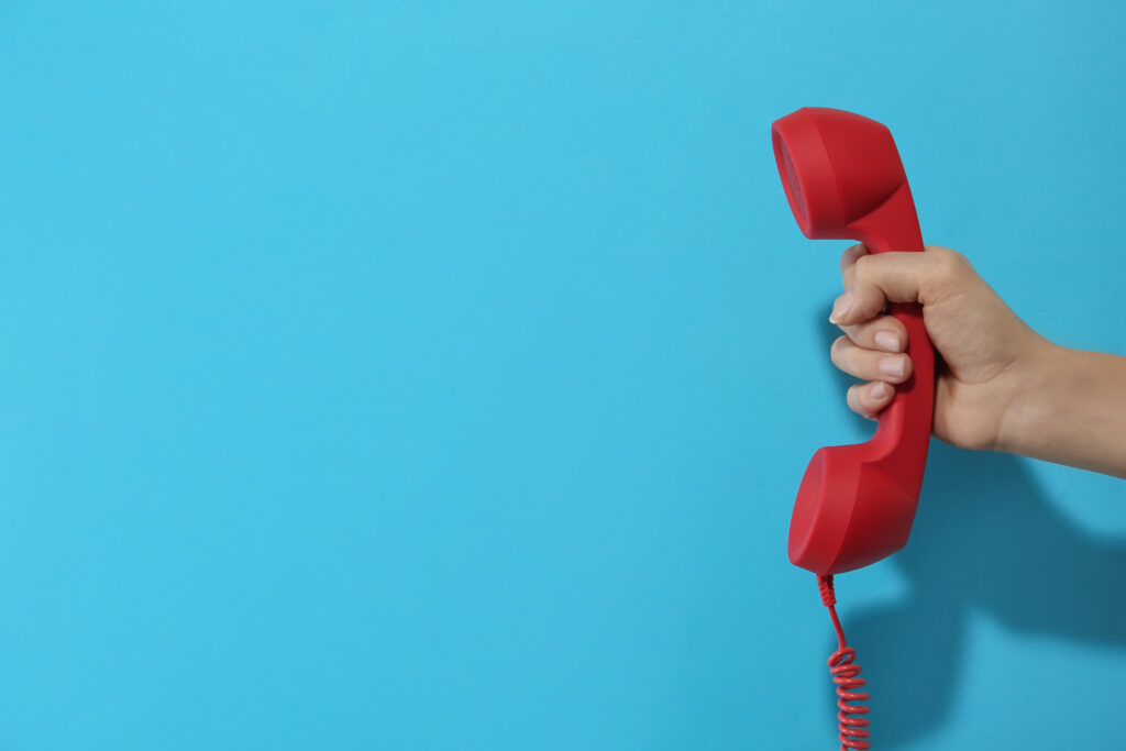 Closeup View Of Woman Holding Red Corded Telephone Handset On Li