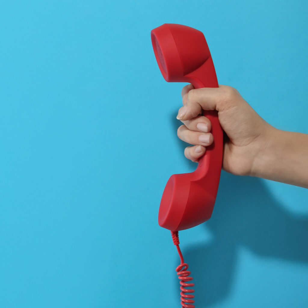 Closeup View Of Woman Holding Red Corded Telephone Handset On Li